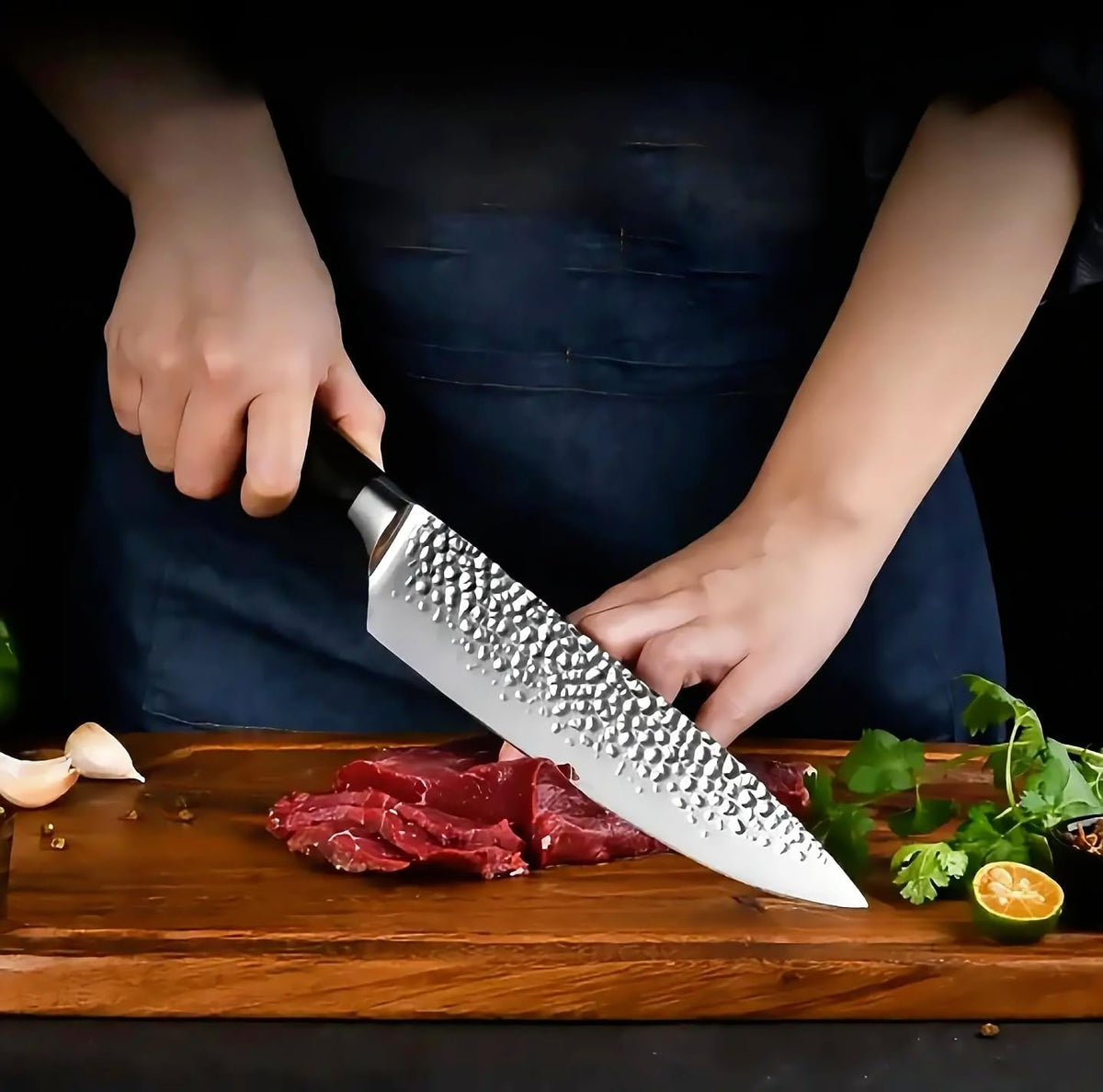 Cook slicing beef on a wooden board with the Elite Chefs 8-inch hammered chef knife, garlic and cilantro alongside